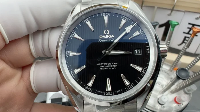Held in a gloved hand from the front, black dial and date at 3