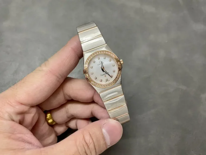 The 25mm rose gold tone model held between two fingers to show its size