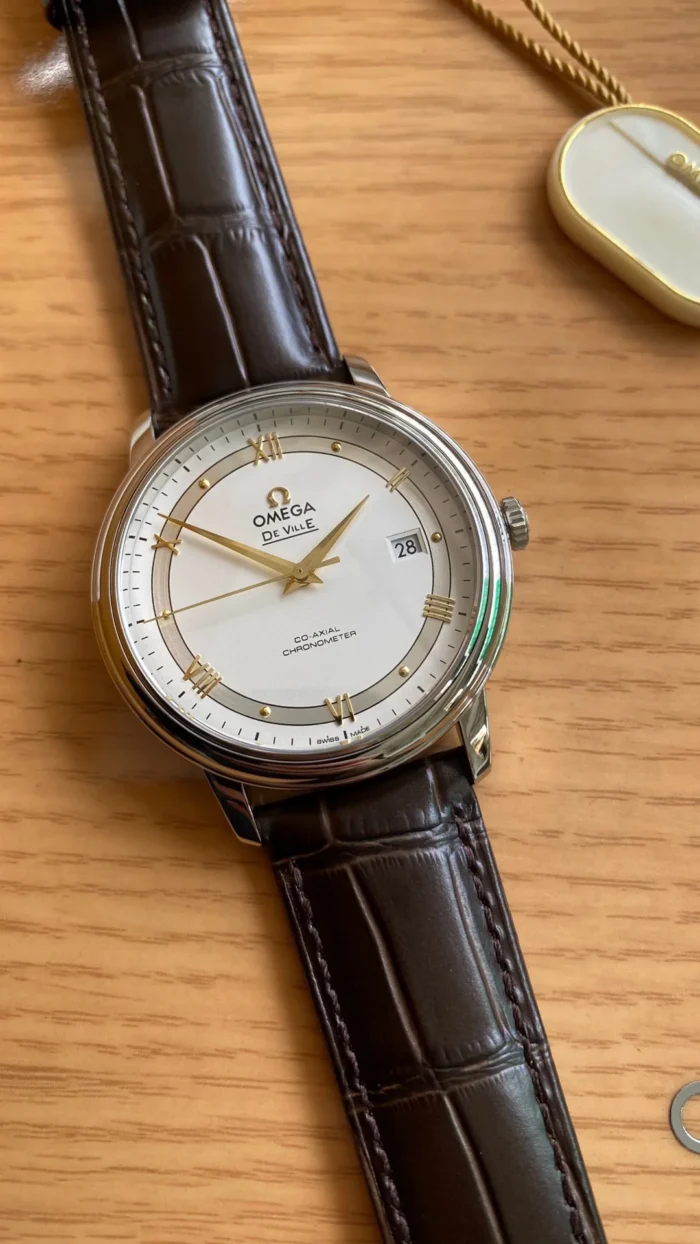 White dial on a wooden box with gold tone hands and Roman numerals