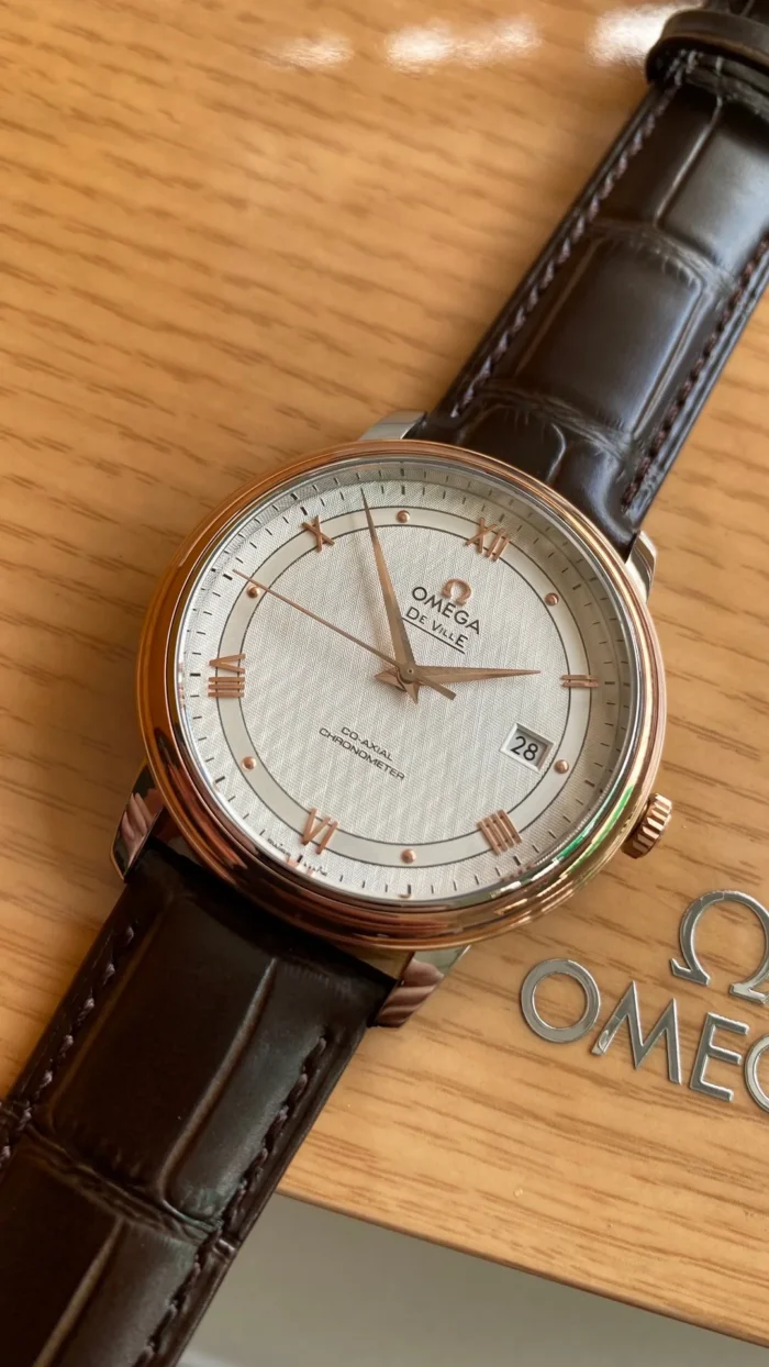 Omega De Ville 39.5mm 424.23.40.20.02.001 on its box, rose gold tone bezel and silver tone case