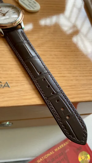 Dark brown alligator pattern strap laid on a wooden box