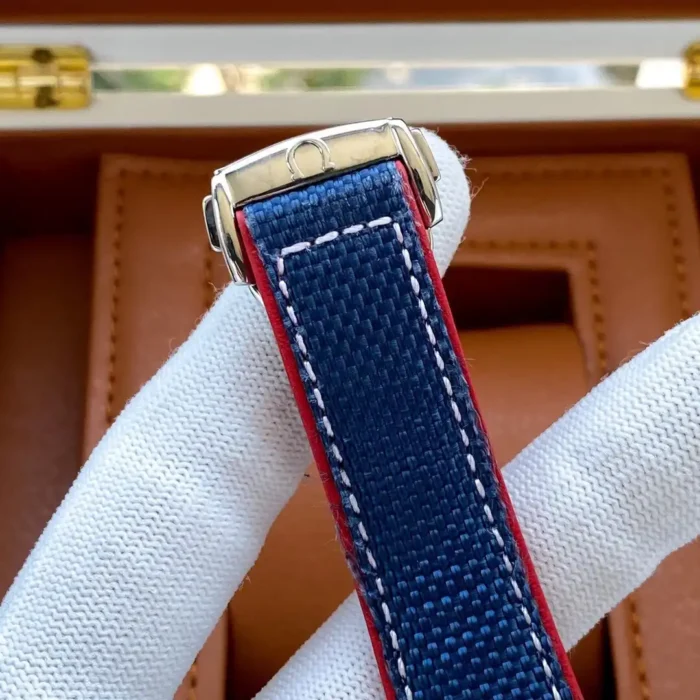 Blue textile strap with red edge and white stitching, held in a glove