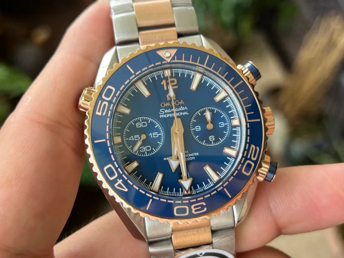 Held in hand from the front, rose gold tone bezel edge and blue subdials