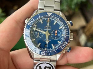 Blue chronograph dial in hand, plants in the background