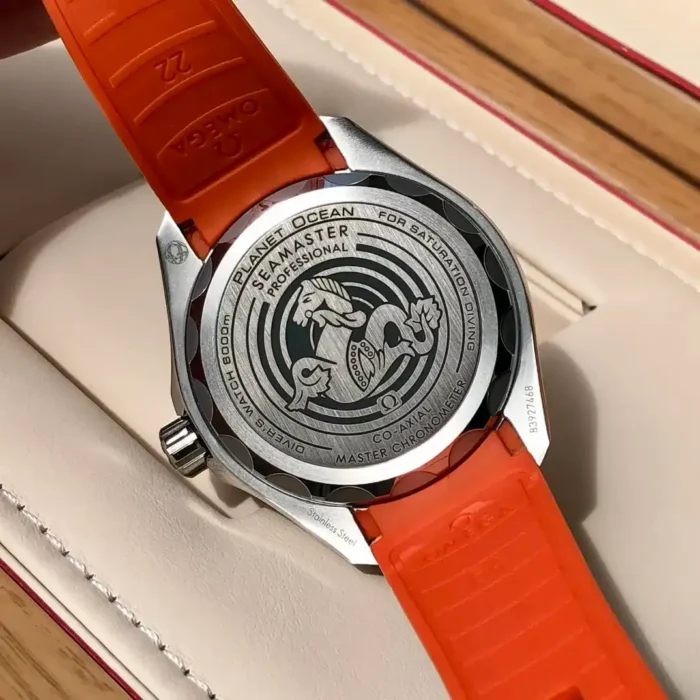 Solid caseback with the seahorse emblem, orange strap underside