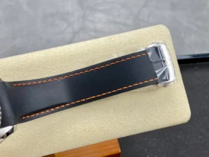 Black rubber strap with orange stitching and the buckle