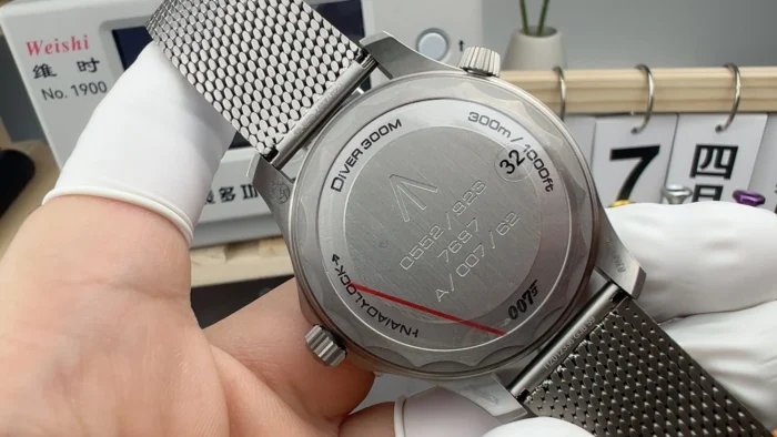 Solid caseback engraved 007 and Diver 300M, held in finger cots