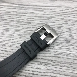 Black rubber strap with an Omega signed pin buckle on wood grain