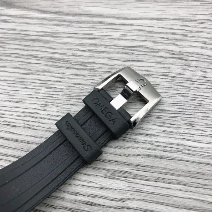 Black rubber strap with an Omega signed pin buckle on wood grain