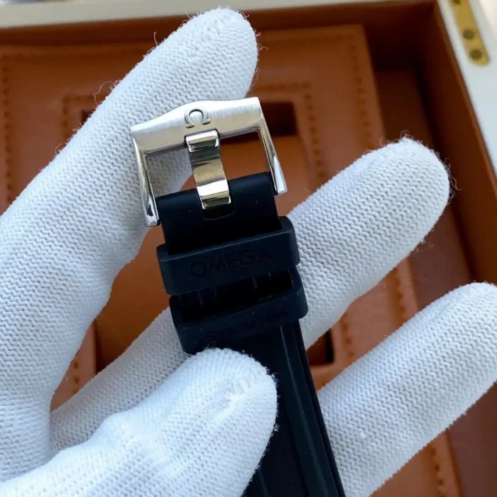 Black rubber strap with an Omega pin buckle, held in a white glove