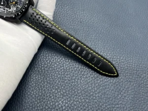 Tail of the perforated black strap with yellow stitching